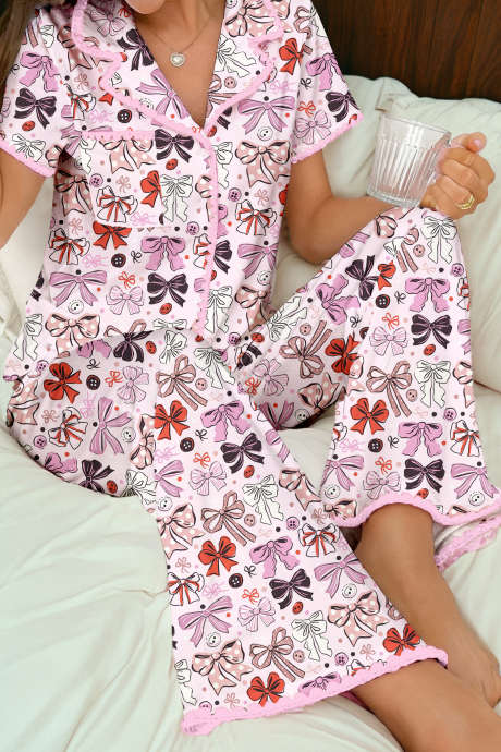 Conjunto de pijama rosa com blusa de manga curta, botões estampados e detalhes em renda.