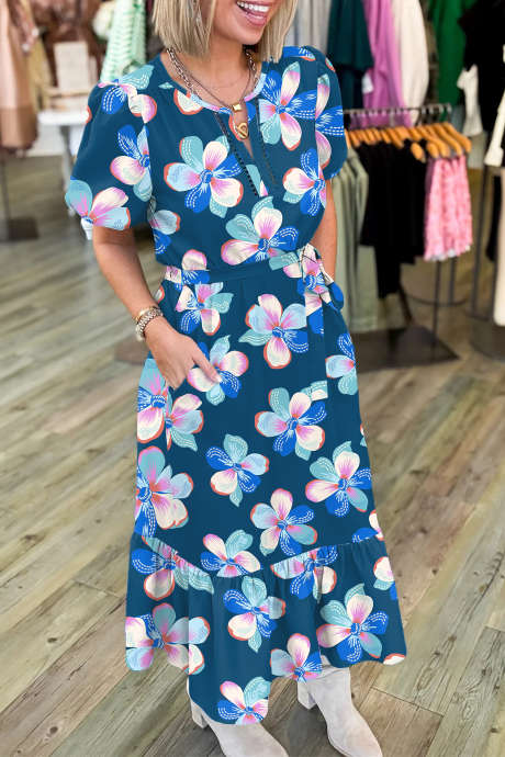 Vestido longo azul com estampa floral, mangas curtas bufantes, barra com babados e cinto.