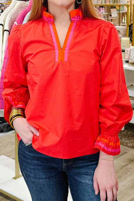 بلوزة مخططة بلون أحمر ناري متباين مع رقبة منقسمة وأكمام طويلة مكشكشة