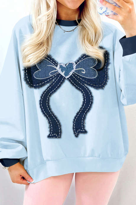 Lichtblauwe denim sweatshirt met rafelige randen en opgestikte strik. Kleurblokken