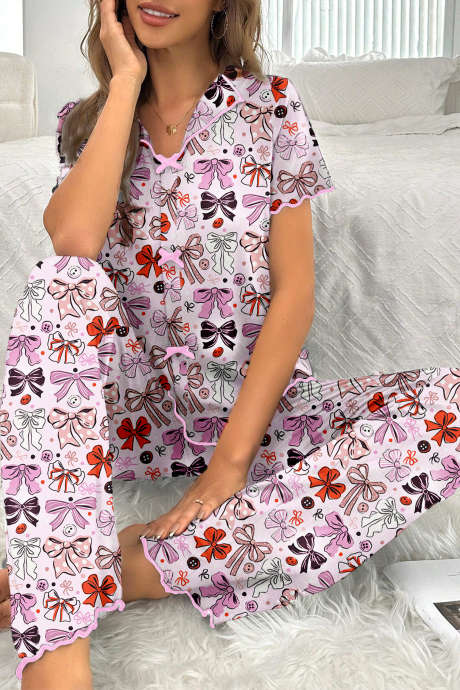Ensemble chemise à manches courtes et pantalon de pyjama rose à motifs de nœuds et boutons, avec bordures contrastées.