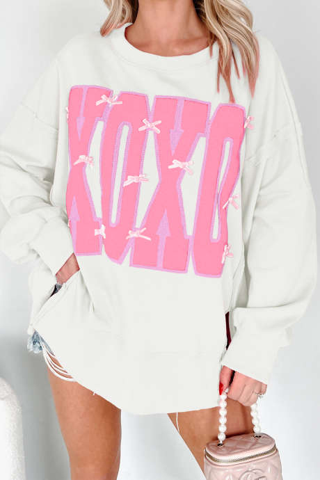 Witte XOXO-sweater met strik en pailletten, met zichtbare naden en een grafische letterprint