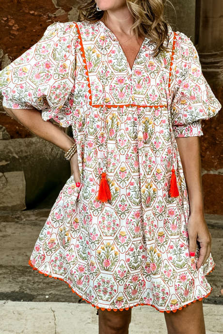 Roze mini-jurk met bloemenprint, kwastjes, V-hals en geschulpte details.