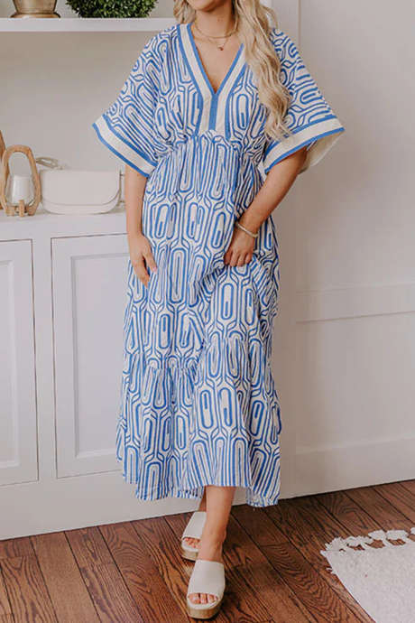 Vestido longo azul celeste com estampa étnica geométrica, detalhes em blocos de cores e decote em V, mangas curtas.