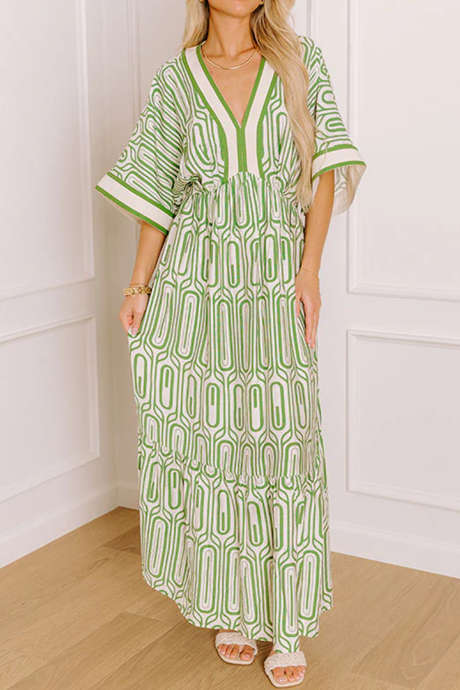 Vestido longo verde com estampa geométrica étnica, detalhes em blocos de cores, decote em V e mangas curtas.