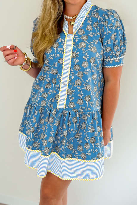 Niebieska sukienka w dużym rozmiarze z kwiatowym nadrukiem w paski i ozdobnymi guzikami z przodu i falbanką na dole