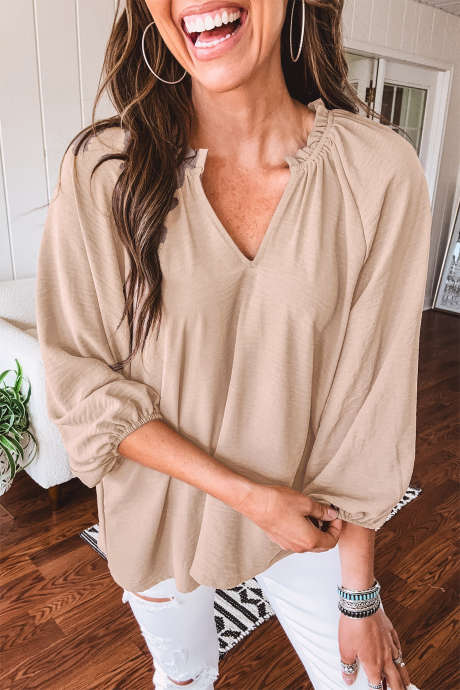 Blusa color pergamino con escote en V, puños fruncidos y mangas tres cuartos.