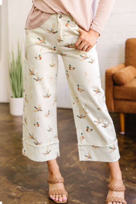 Quần jeans ống suông màu be thời trang in họa tiết vịt trời, gấu quần xắn lên.