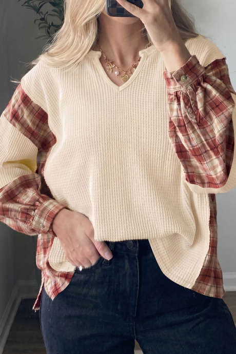 Blusa bege com textura waffle, decote em V, estampa xadrez colorblock, ombros caídos e mangas compridas.