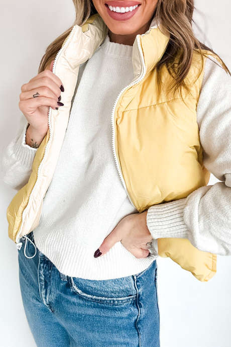 Colete acolchoado reversível em pergaminho, com gola alta, bolso com zíper e cores contrastantes.