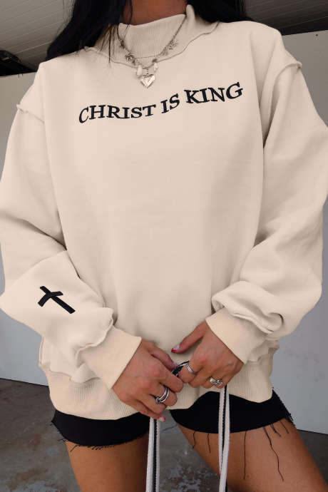 Sweatshirt longgar berkerah tinggi dengan bordir tulisan CHRIST IS KING warna krem.