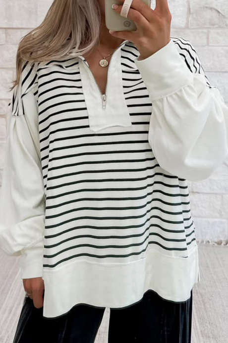 Top largo con mangas abullonadas y cuello con cremallera metálica, bloques de color y rayas blancas.