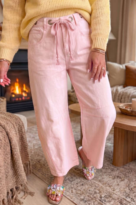 Lichtroze effen jeans met metalen oogjes en knoop in de taille.