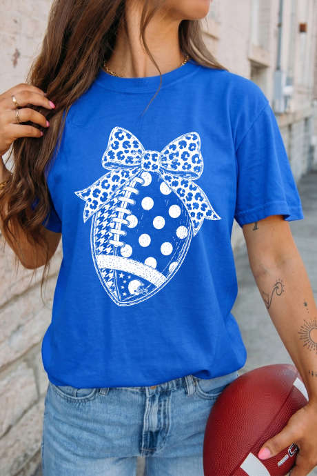 Camiseta azul-escura com estampa de leopardo, laço e bolinhas, perfeita para o dia do jogo de futebol.