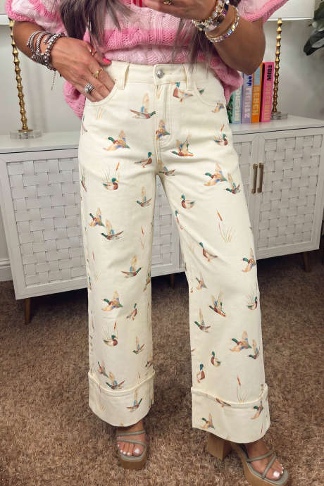 Calça jeans bege com estampa de pato-real e barra dobrada.