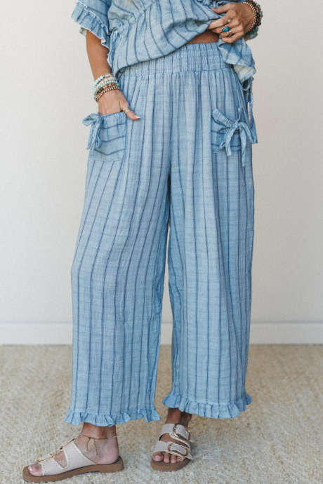 Pantaloni casual a righe azzurre con elastico in vita, dettaglio fiocco, tasche e orlo a balze.
