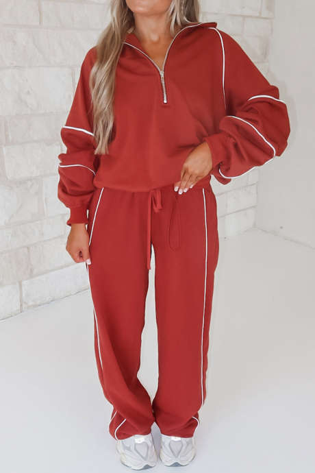 Conjunto de pantalón deportivo rojo de carreras con detalle de ribete, media cremallera y cordón ajustable.