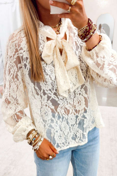 Blusa beige de manga larga con cuello de encaje floral y lazo.
